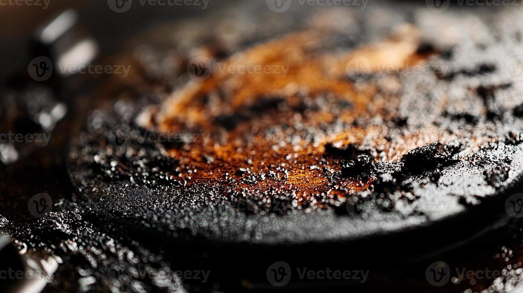 Close-up of blackened residue clinging to a stovetop burner surface photo