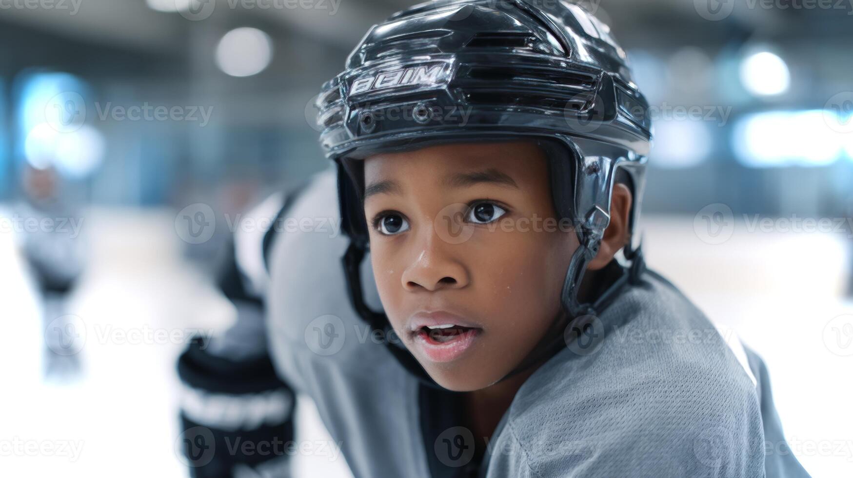 A young African American boy showcases his hockey skills by passing a puck across the ice, during a practice session at a local ice rink in winter. photo