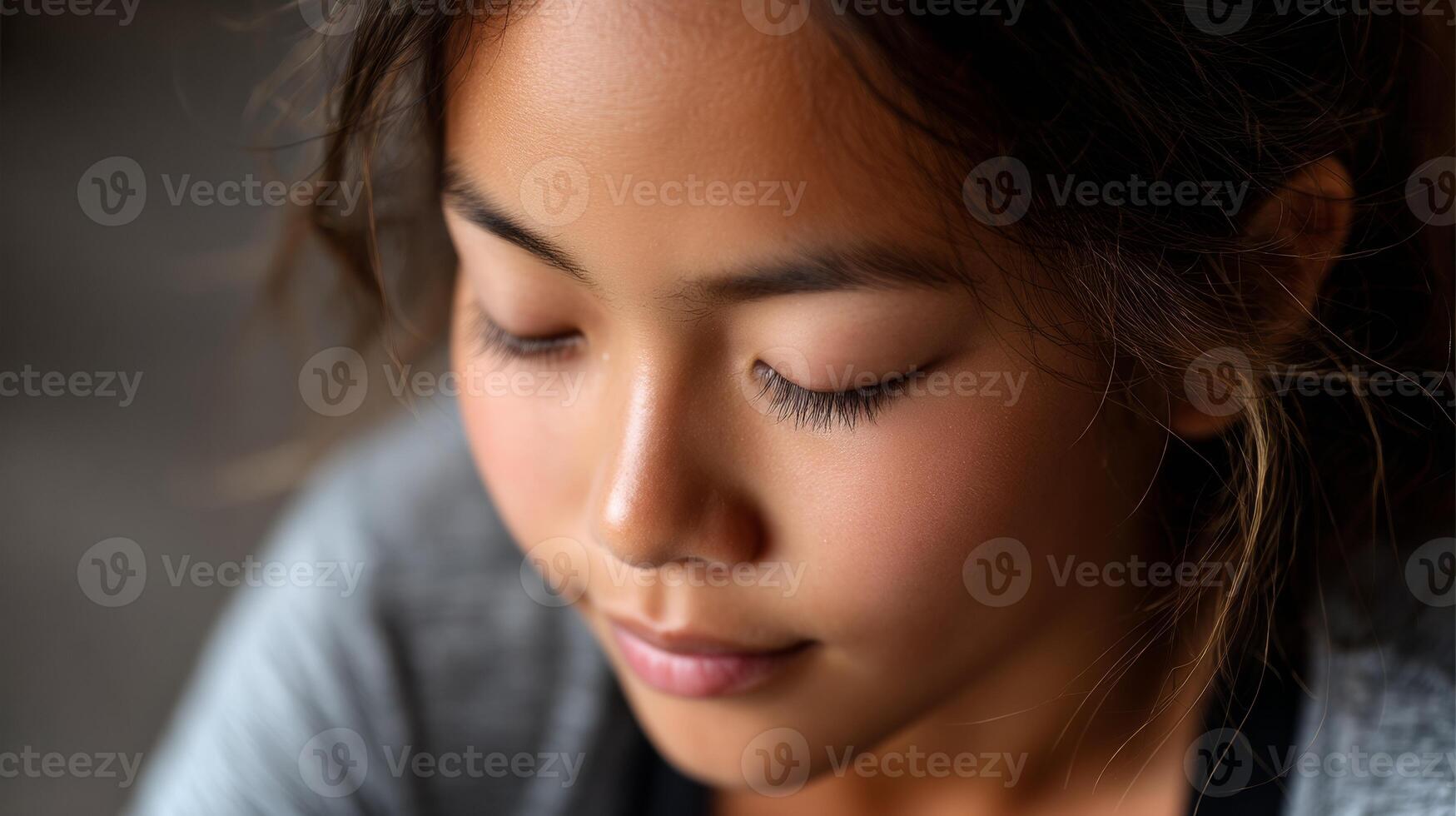 A young Asian girl practices yoga with a focused expression while performing a forward fold. Natural light highlights her calm demeanor and gentle features. photo