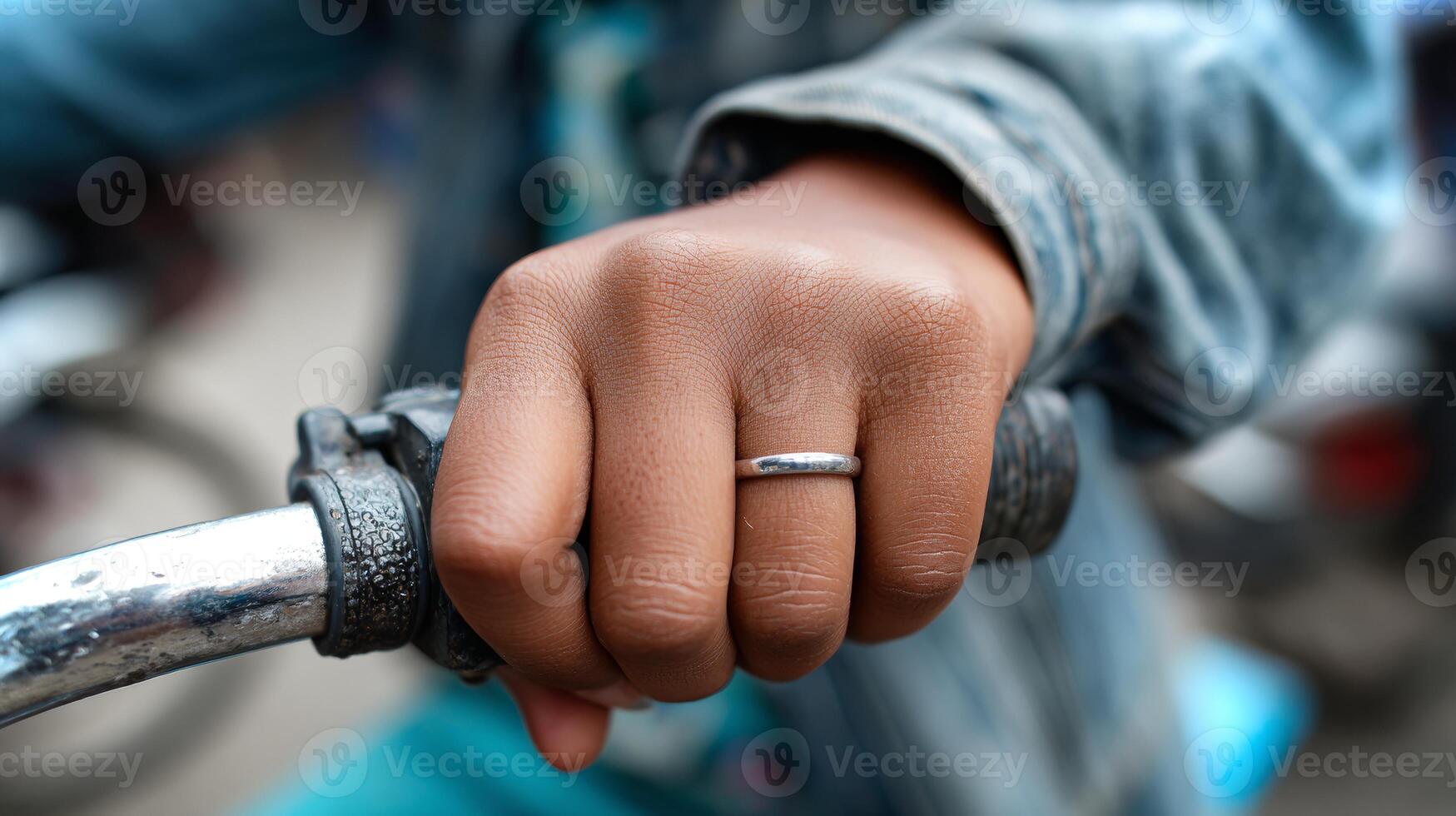 A close-up view of a South Asian girl's hand gripping a bicycle handlebar. The grip tape is peeling, highlighting adventurous use as she rides outdoors. photo