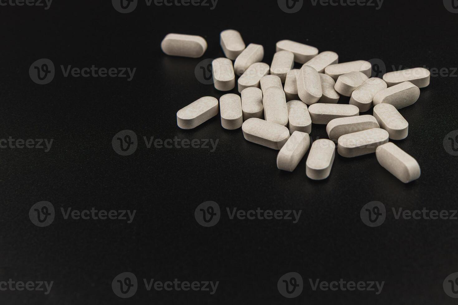 Tablets scattered on a dark surface depicting health supplements photo