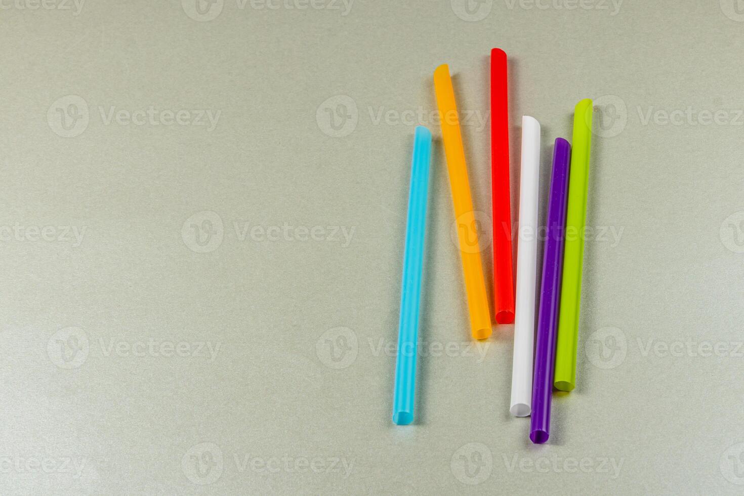 Colorful straws arranged on a light gray background photo