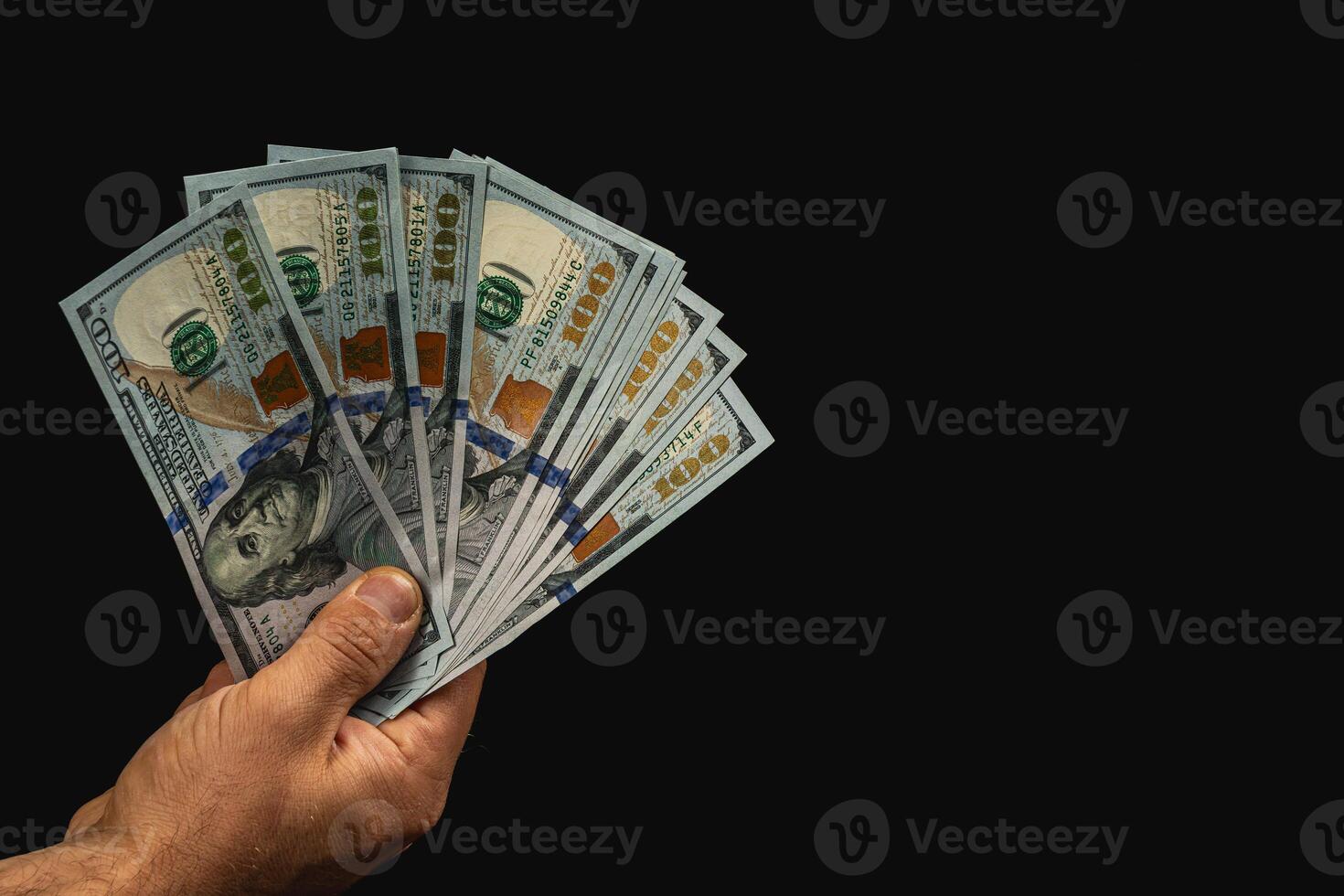 Hand holding bundles of cash against a dark background photo