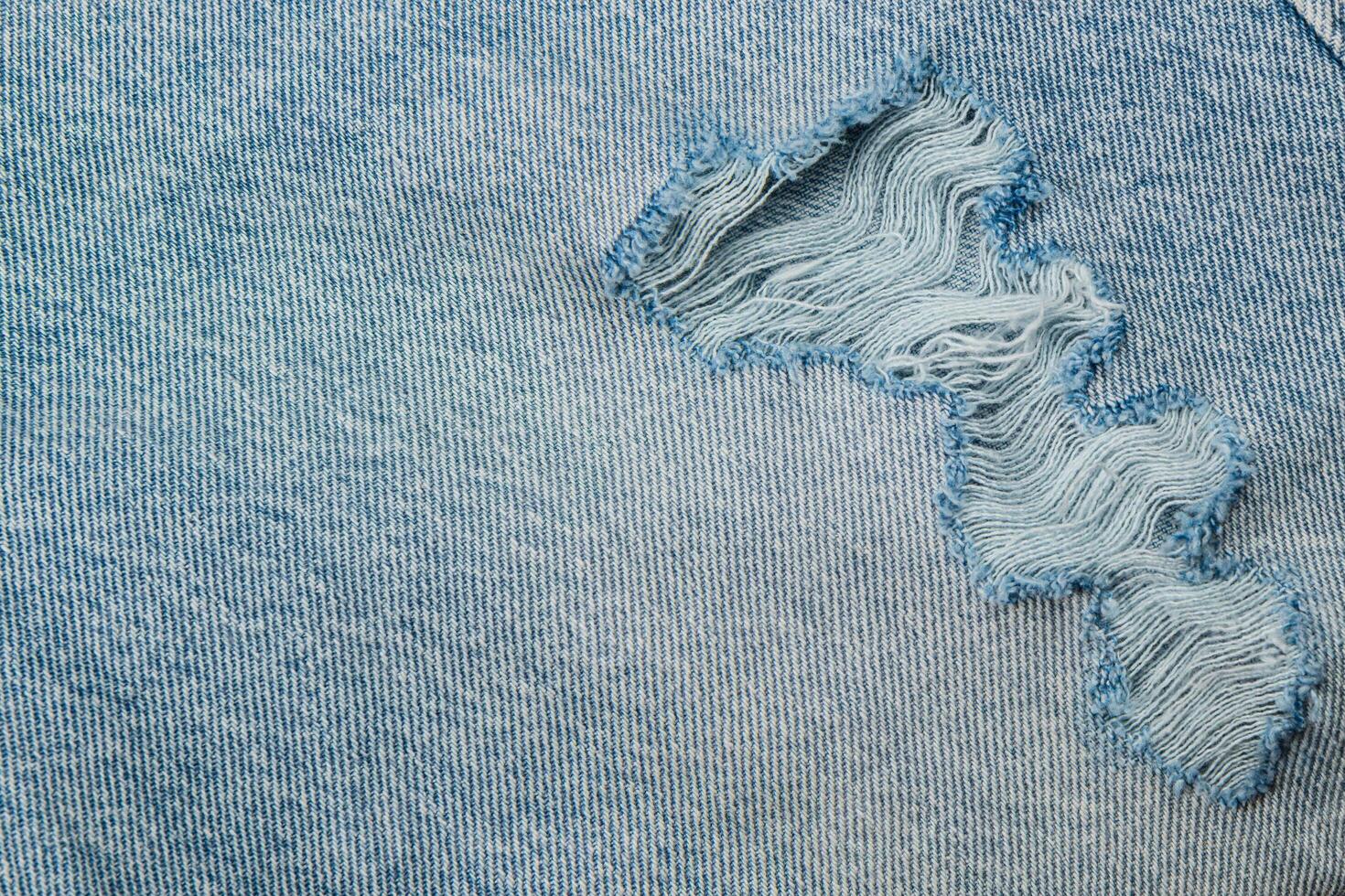 Denim fabric with a visible tear and frayed edges photo