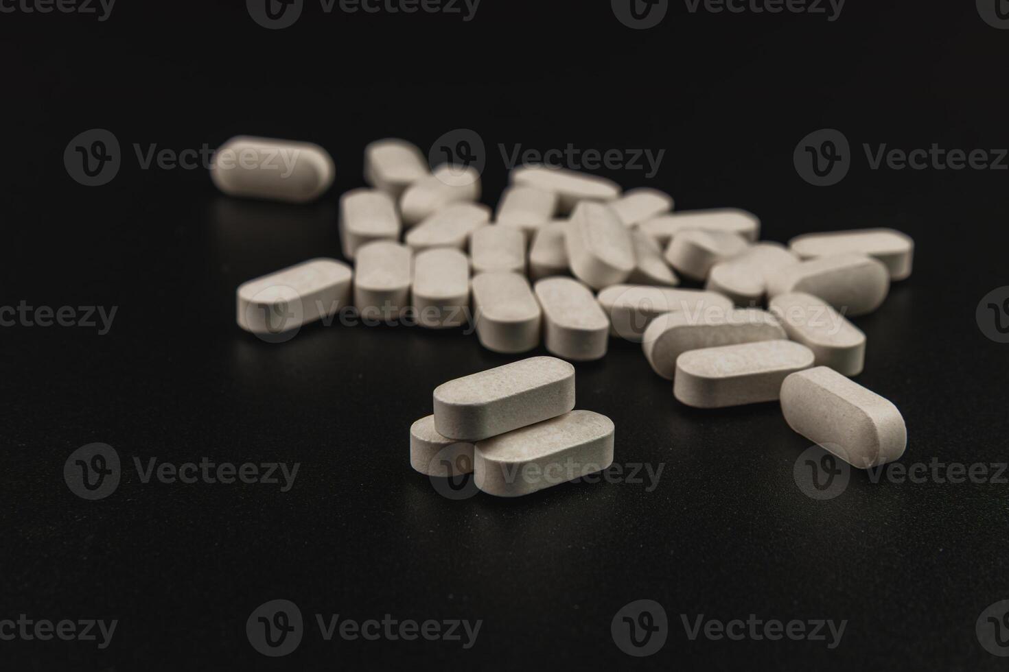 White tablets scattered on a dark surface in a close-up view photo