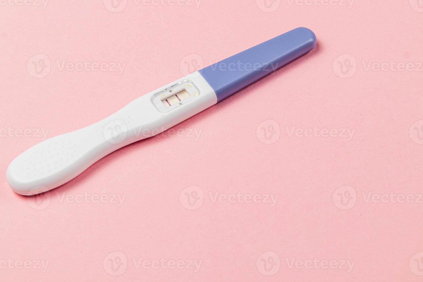 Pregnancy test showing two lines on a pink background photo