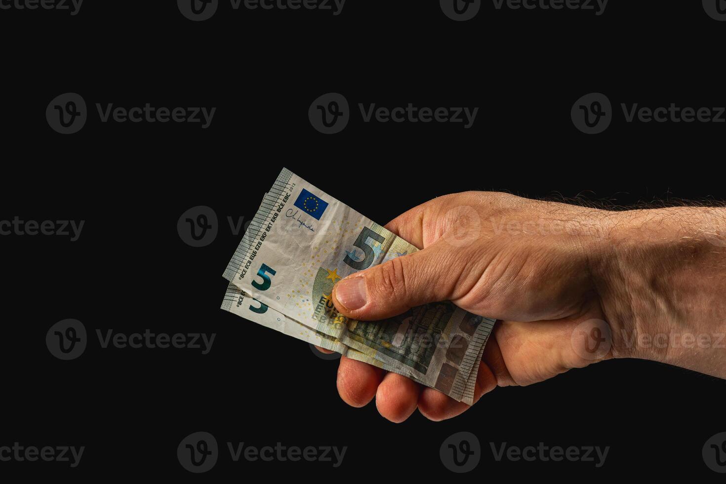 Person holding five euro banknotes in dark surroundings photo