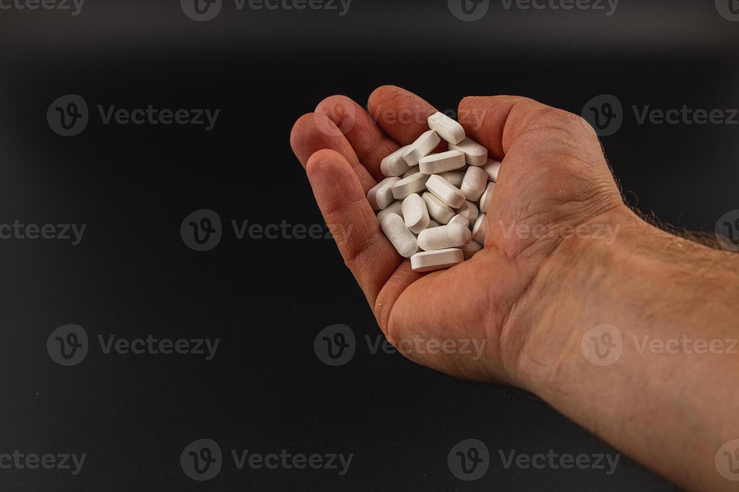 Hand. holding white tablets against a dark background photo