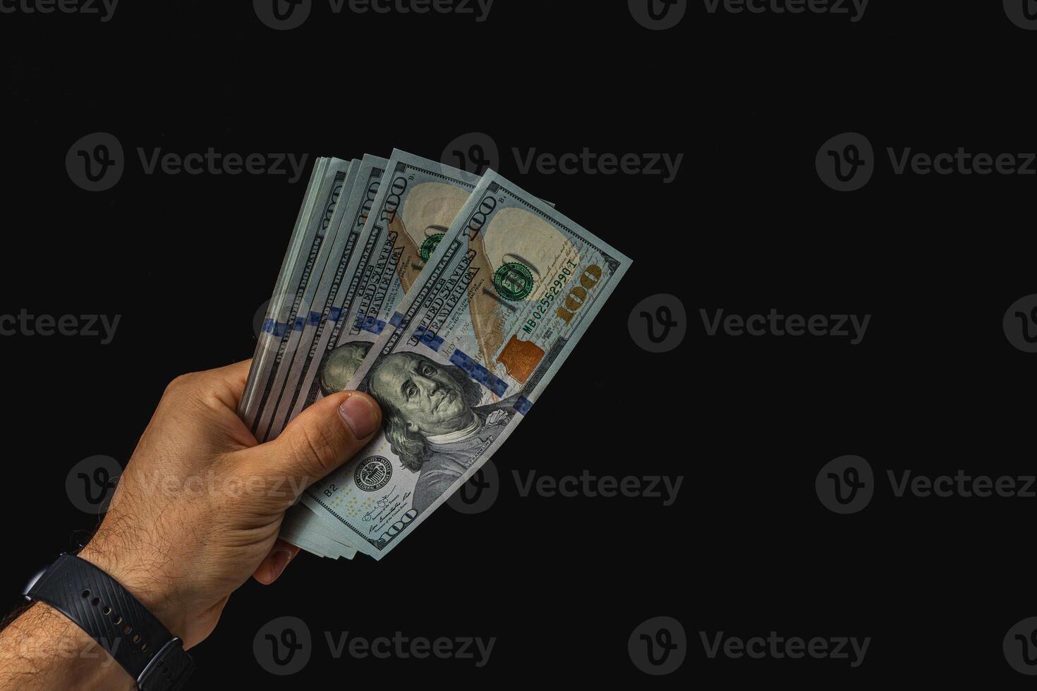 Hand holding cash in a dark setting with focus on bills photo