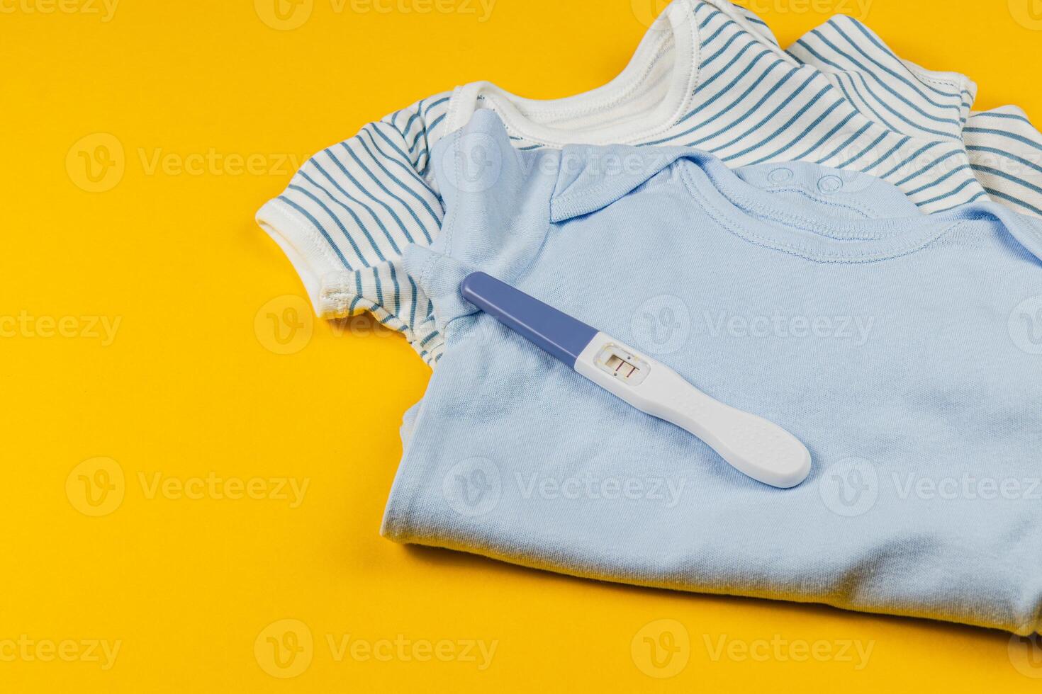 Exciting announcement with baby clothes and pregnancy test photo