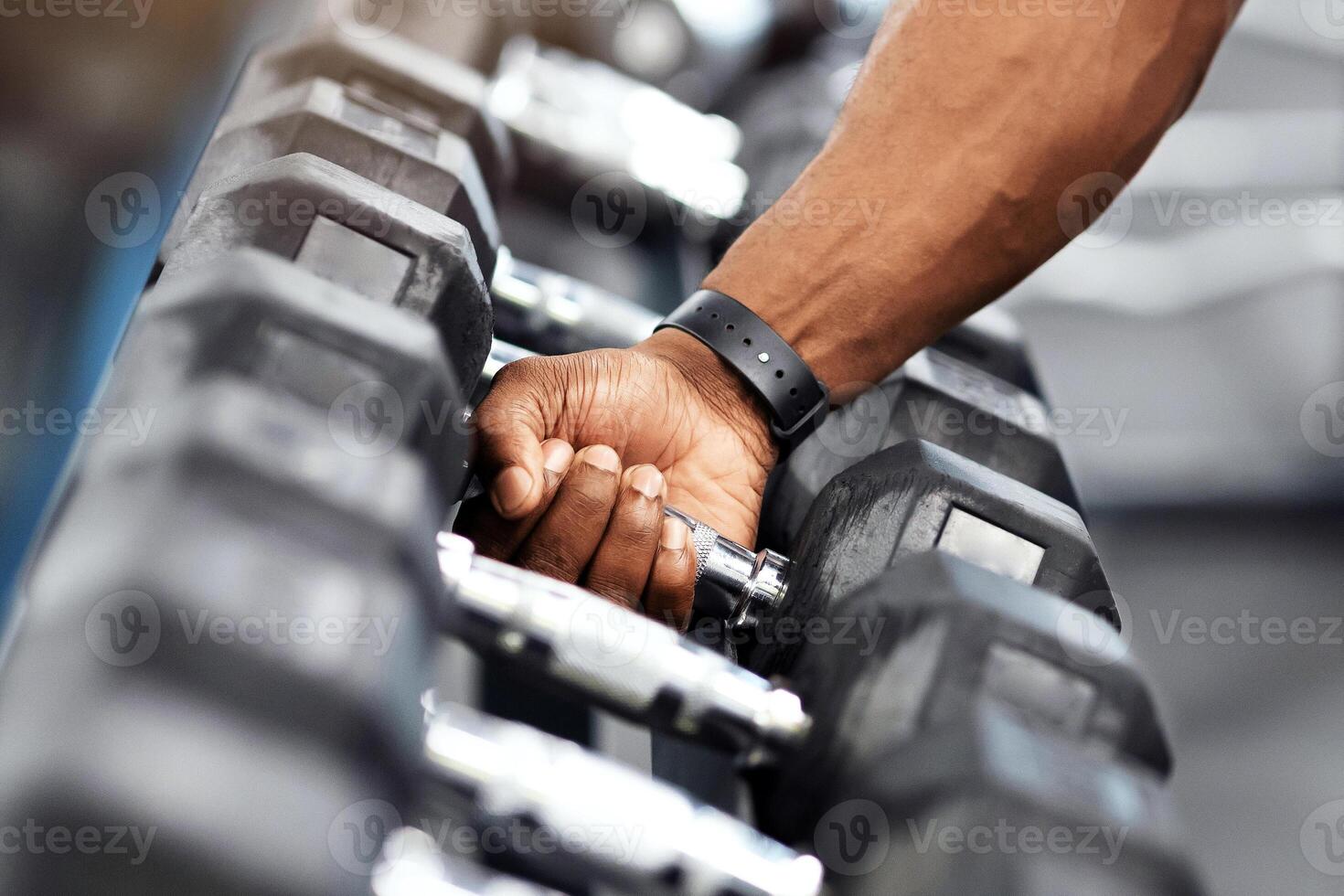 Sports equipment for gym concept. Unrecognizable african american muscular bodybuilder hand grabbing barbell at modern gym, copy space. Cropped of black athletic man working out with dumbbells photo