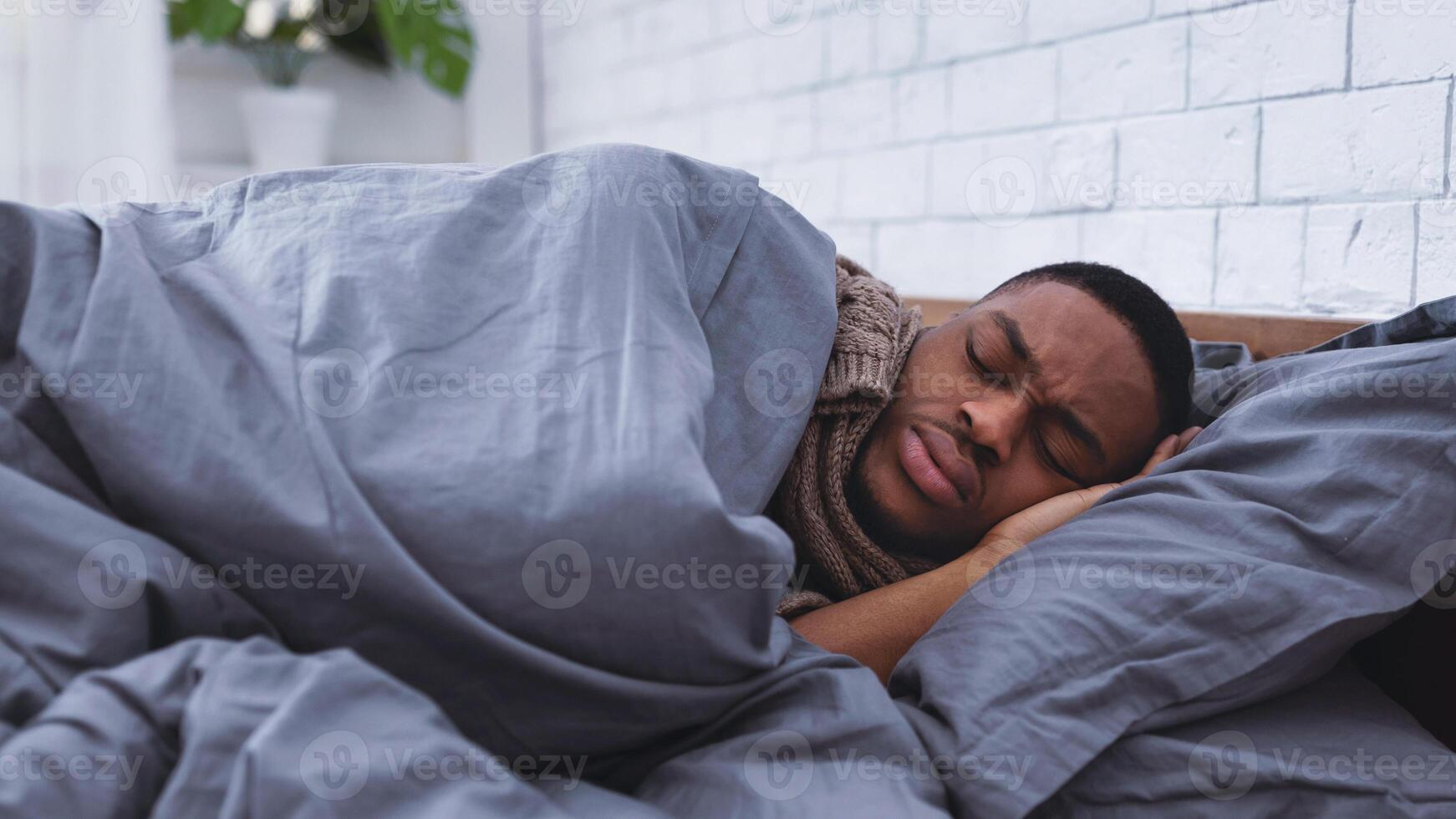 Sick Black Man Sleeping Lying In Bed Having Cold And Flu Symptoms At Home. Ill African American Guy Resting In Bedroom Suffering From Coronavirus Disease. Covid-19 Concept. Selective Focus photo