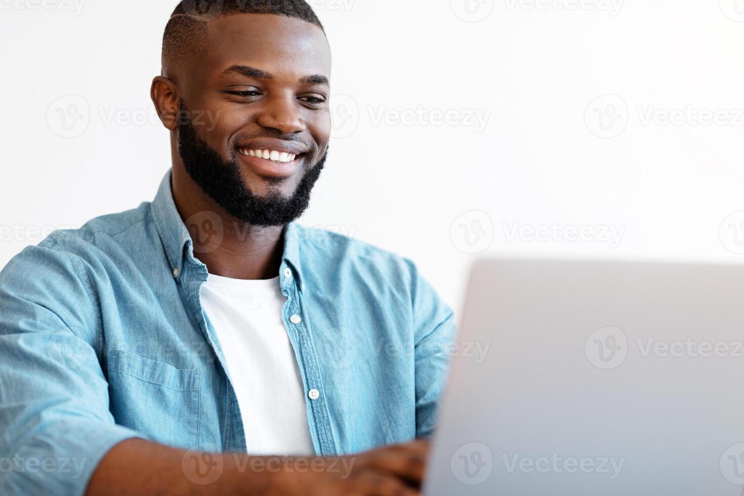 Handsome Black Male Office Employee Working On Laptop Computer, Millennial African American Man Freelancer Sitting At Desk, Typing On Keyboard And Smiling, Enjoying Remote Job, Closeup With Free Space photo