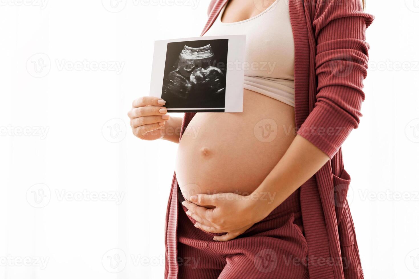 Closeup Shot Of Pregnant Lady Showing Baby Ultrasound Photo And Embracing Belly, Unrecognizable Expectant Woman Showing Sonography Shot While Standing Against Window At Home, Cropped Image