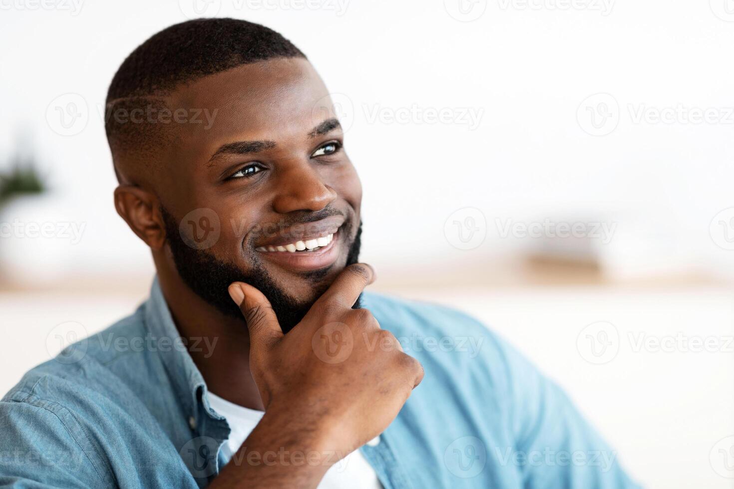 Portrait Of Handsome Smiling African American Man Touching Beard While Looking Away, Attractive Pensive Black Guy Daydreaming, Thinking About Something With Pleased Face Expression, Closeup Shot photo