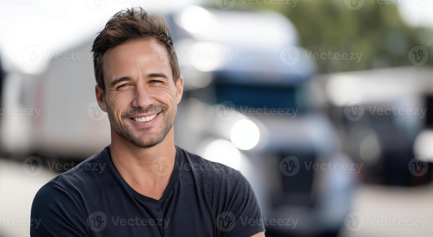 A man in casual attire stands proudly beside a large truck, showcasing his profession as a driver. His confident smile reflects pride in his work. photo