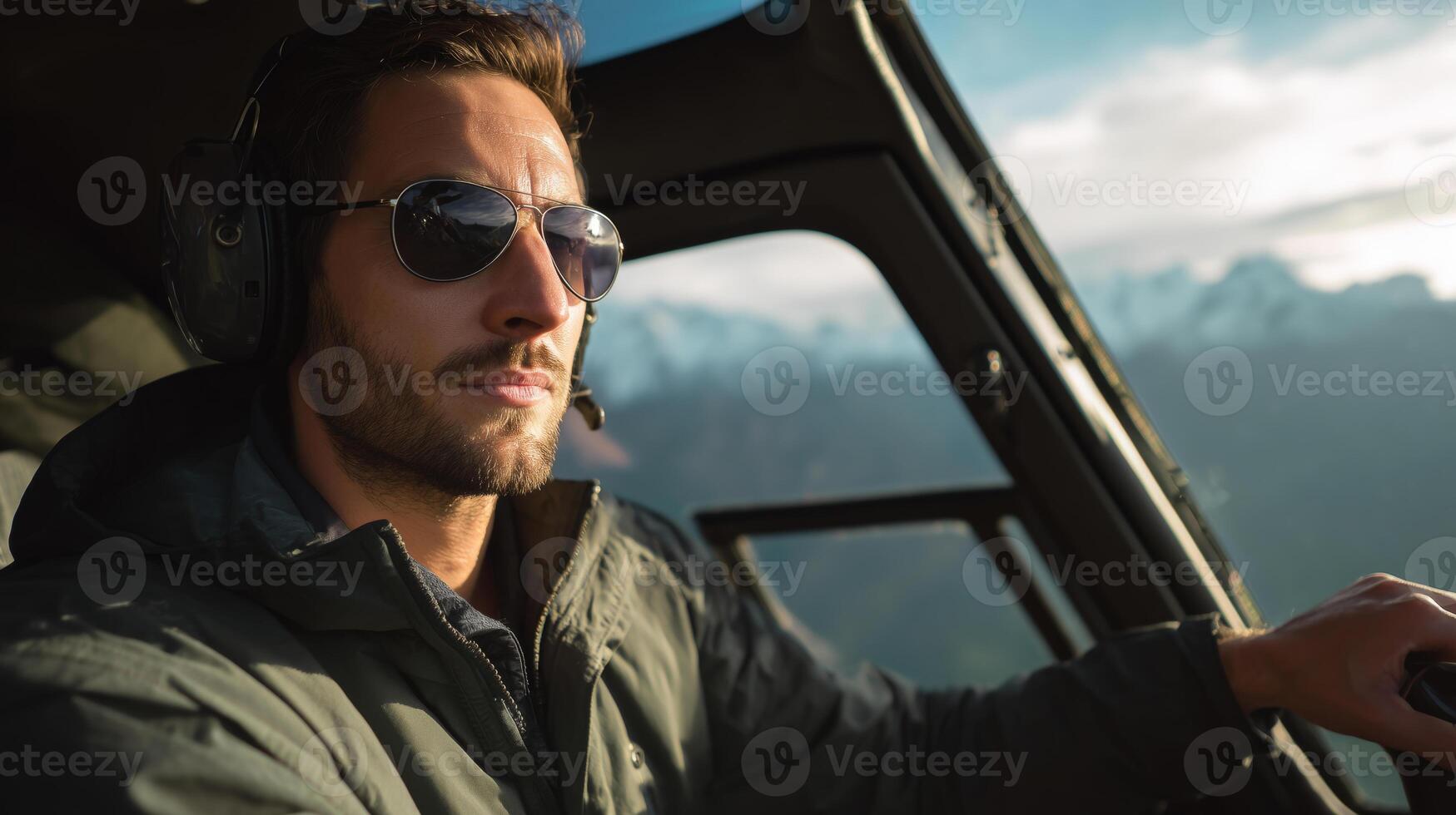 A skilled pilot steers a military aircraft high above the clouds, showcasing concentration and expertise. The mountain range is visible in the background, adding to the dramatic landscape. photo