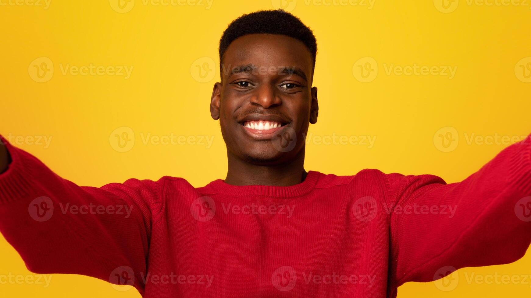 Selfie Time. Cheerful young african american guy making self-portrait and smiling at camera, positive black man taking photo standing isolated over yellow background, closeup shot with free space