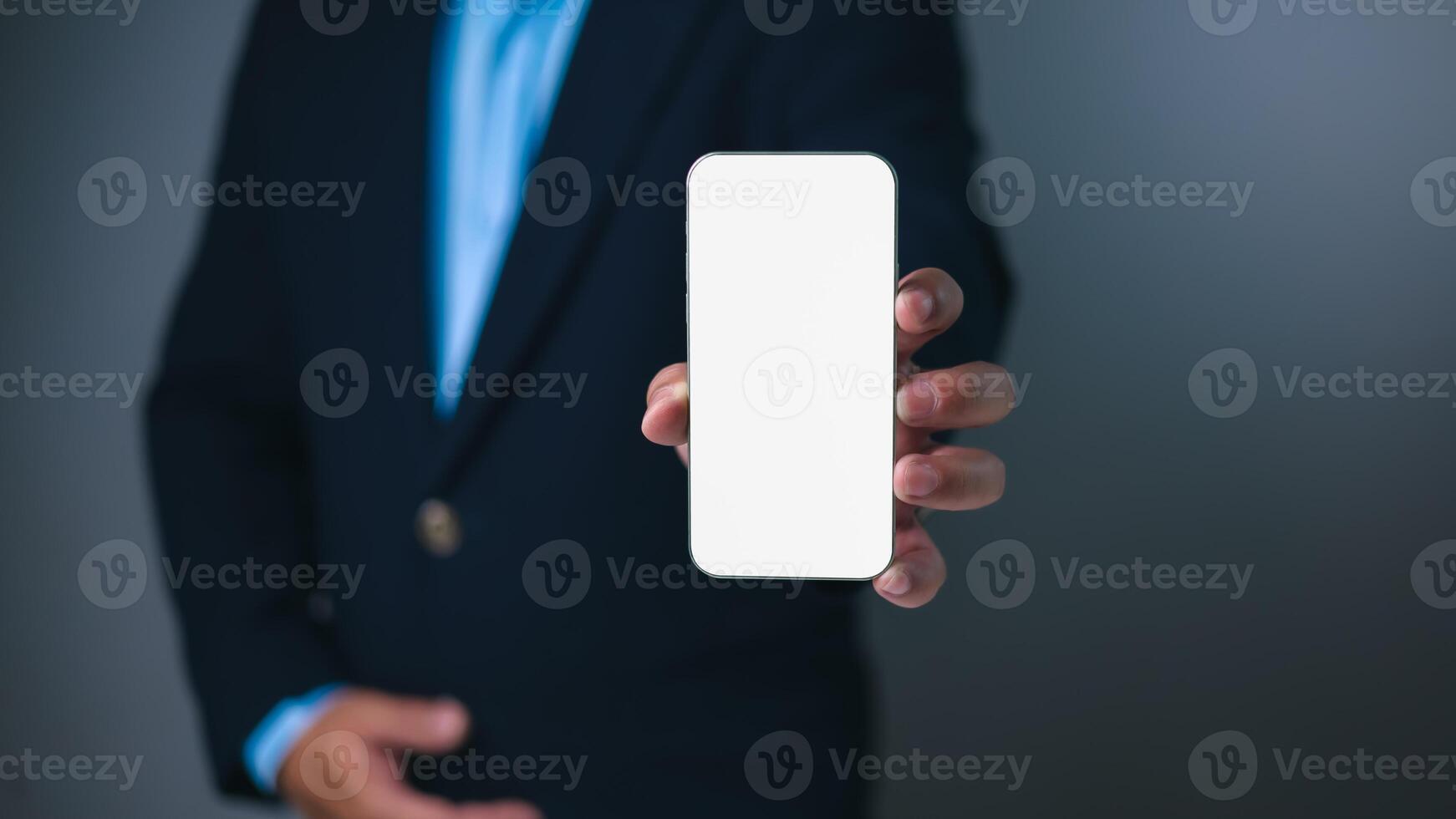 Businessman in a dark suit presents a smartphone with a blank white screen, offering a versatile template for app displays, digital content, or mobile technology concepts. mockup screen phone. photo