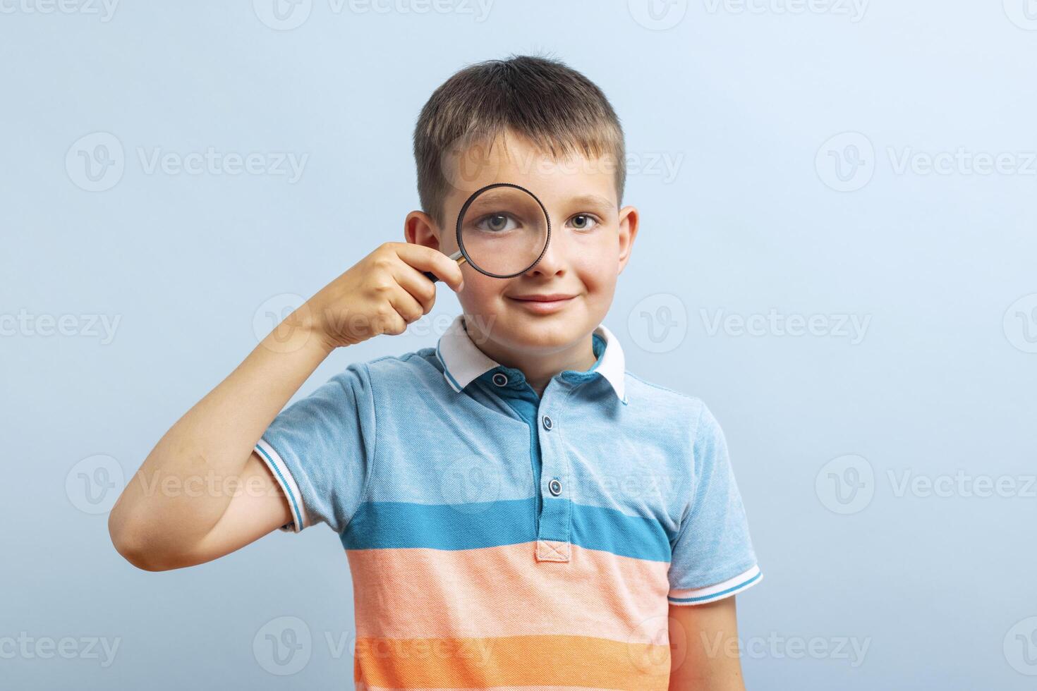 Schoolboy in casual clothes looks through magnifying glass photo