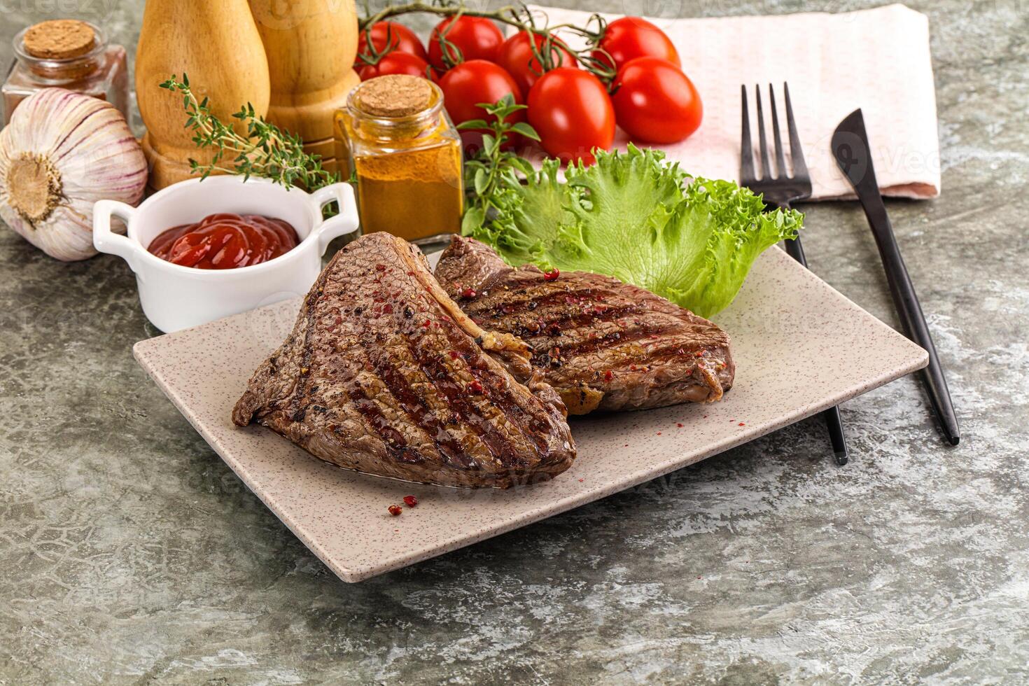A plate with two steaks and a tomato photo