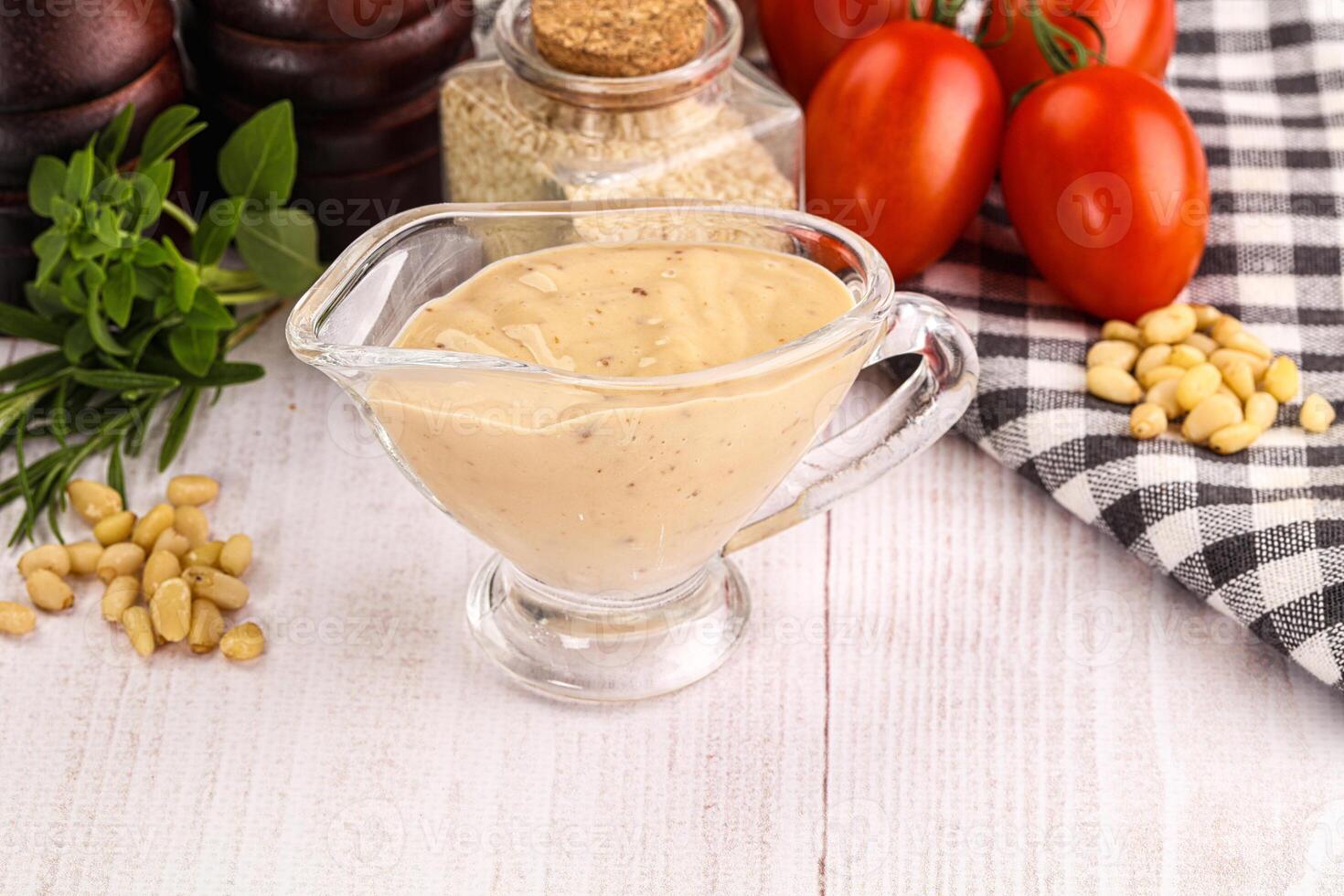 A glass pitcher filled with mustard and tomatoes photo