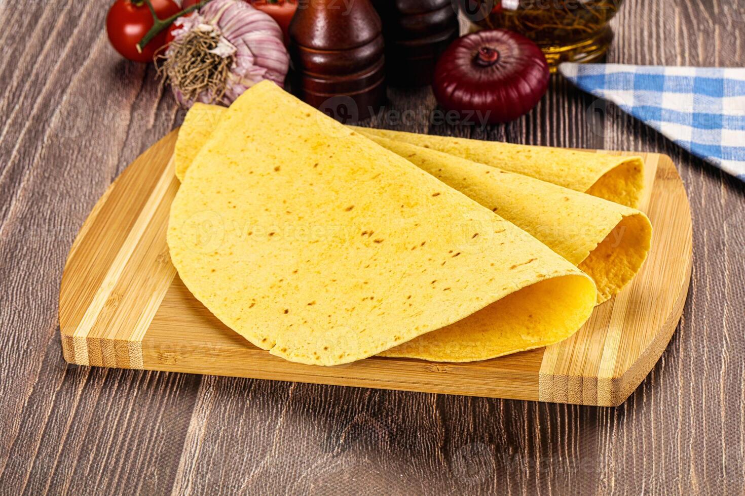 A tortilla on a wooden cutting board with tomatoes and other ingredients photo