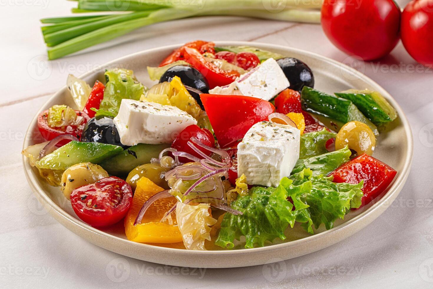 A plate of salad with tomatoes, cucumbers, onions, and feta cheese photo