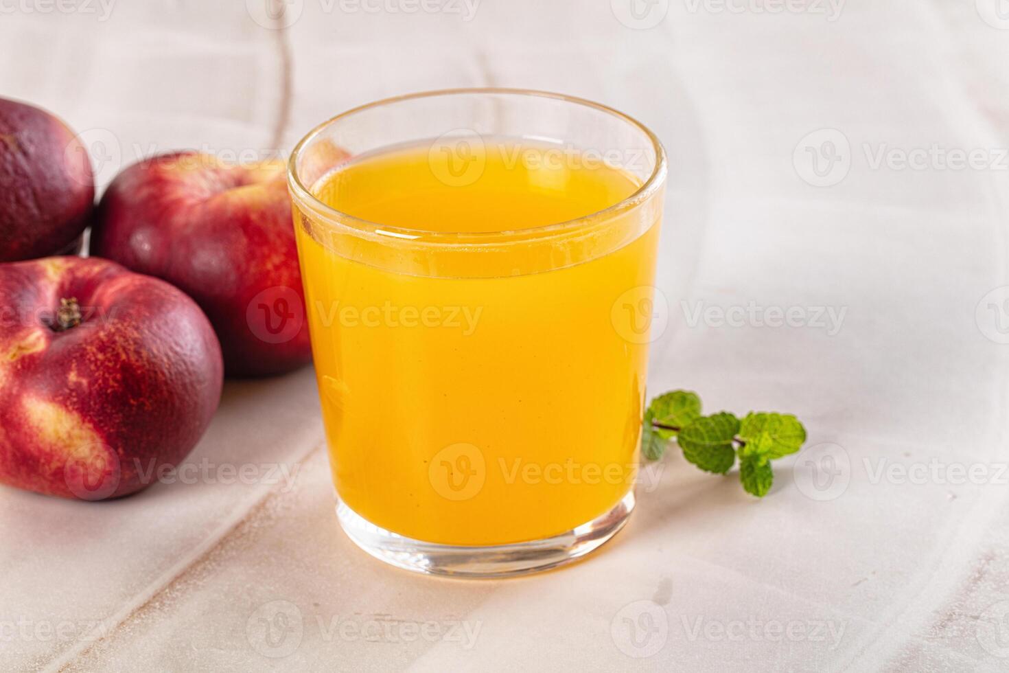 A glass of juice next to some apples photo