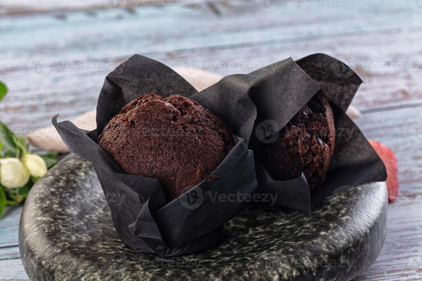 Two chocolate muffins sit on a black plate photo