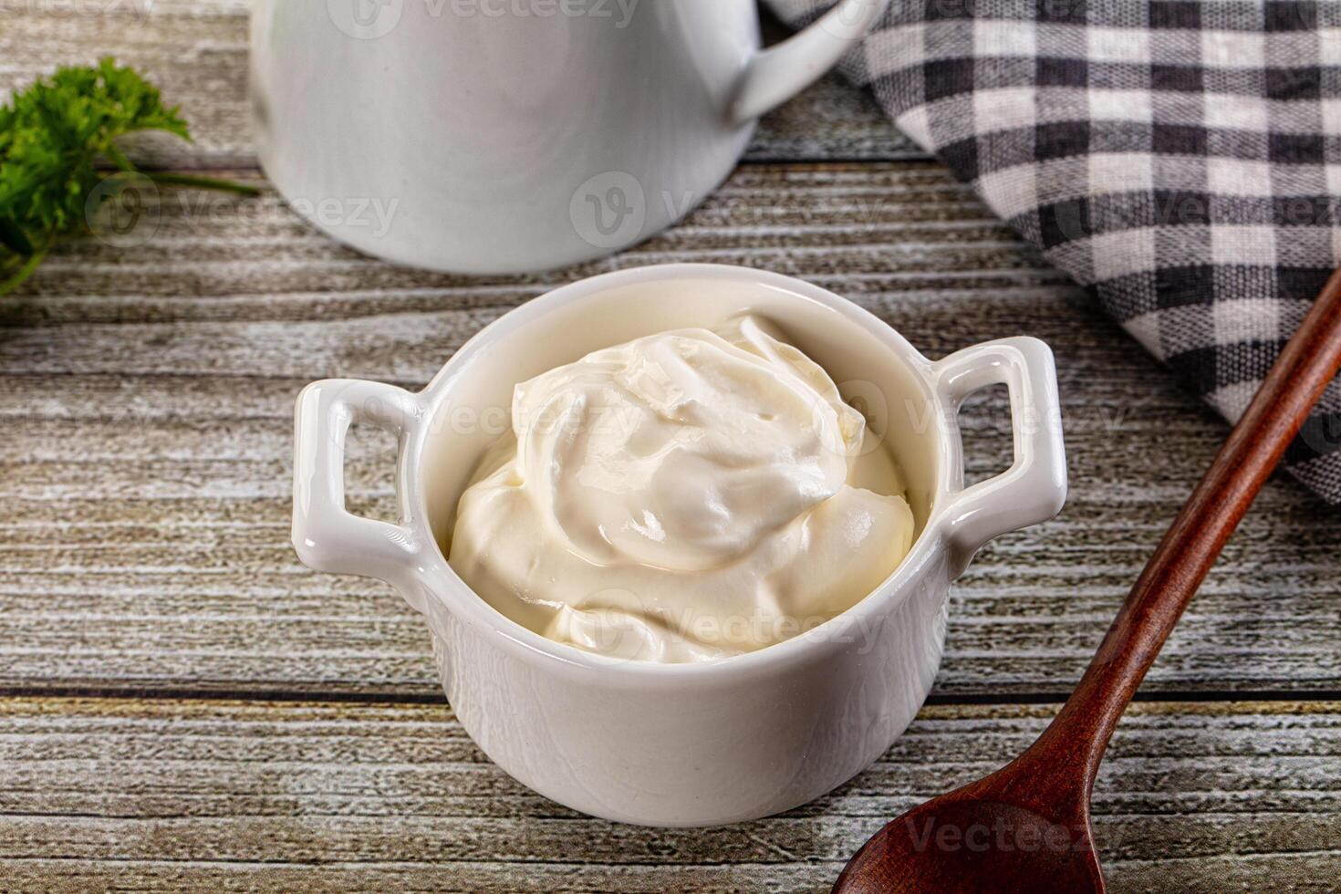 A bowl of sour cream next to a spoon photo