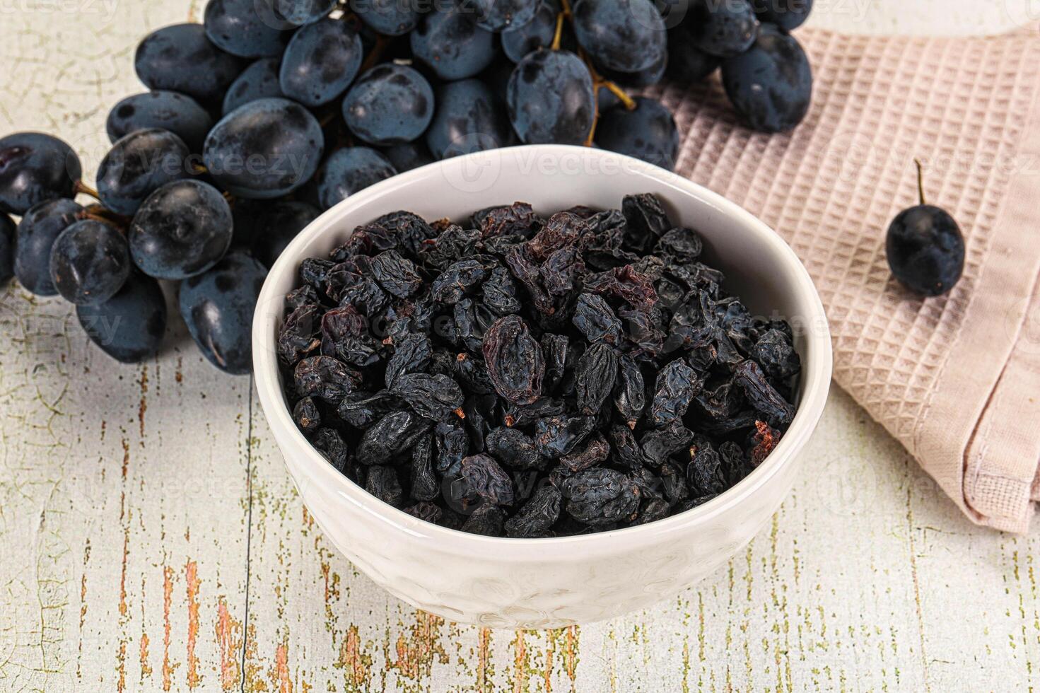 A bowl of dried grapes and a towel on a table photo