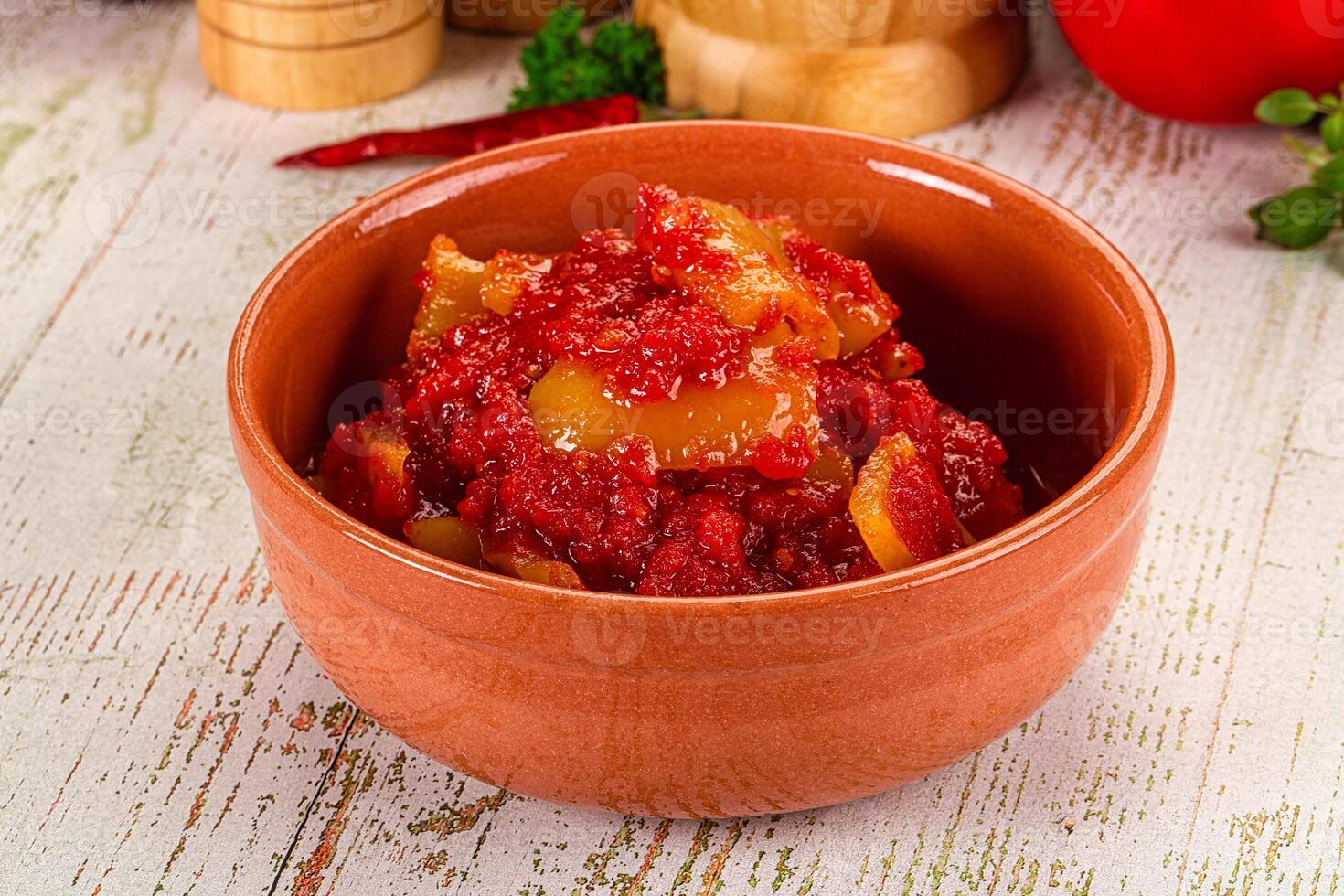 A bowl of red sauce with peppers and other ingredients photo