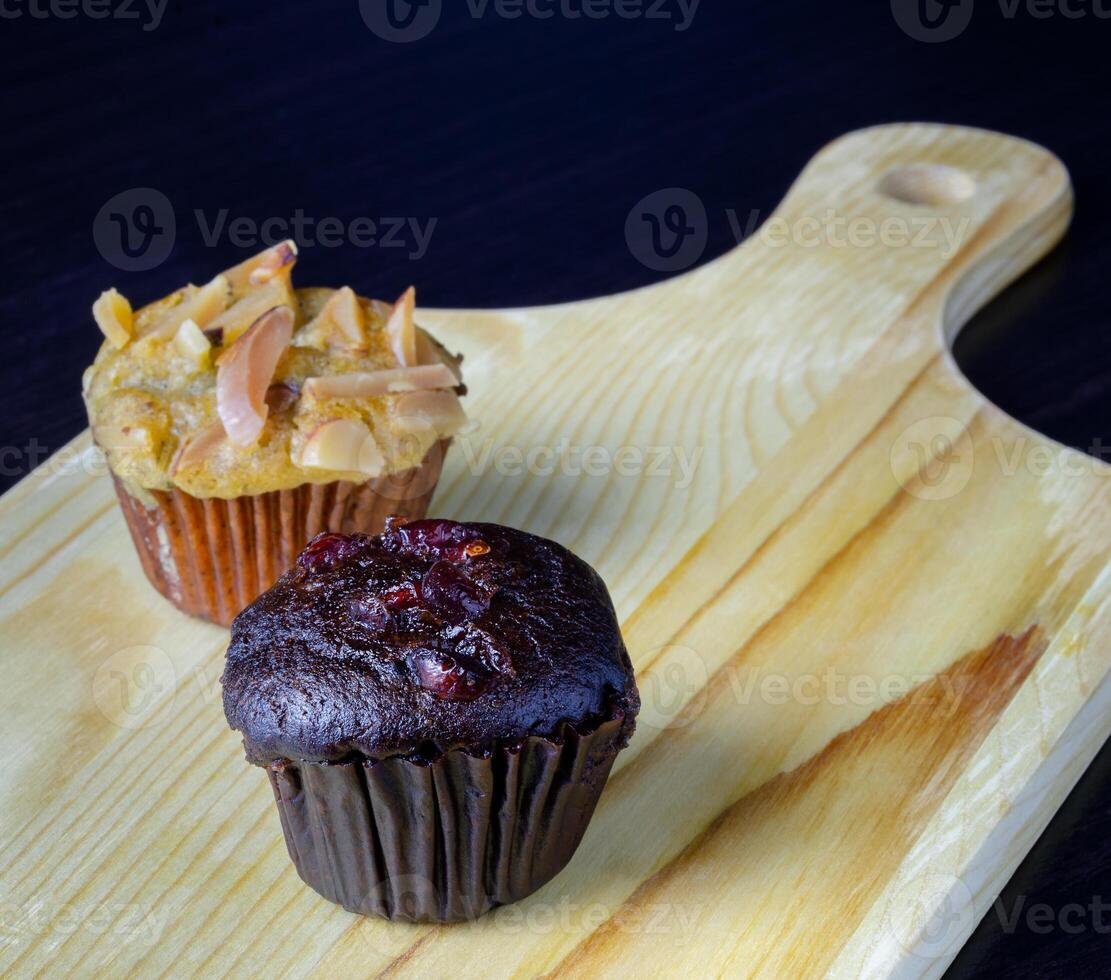 Chocolate muffin and banana cupcake on wooden tray photo