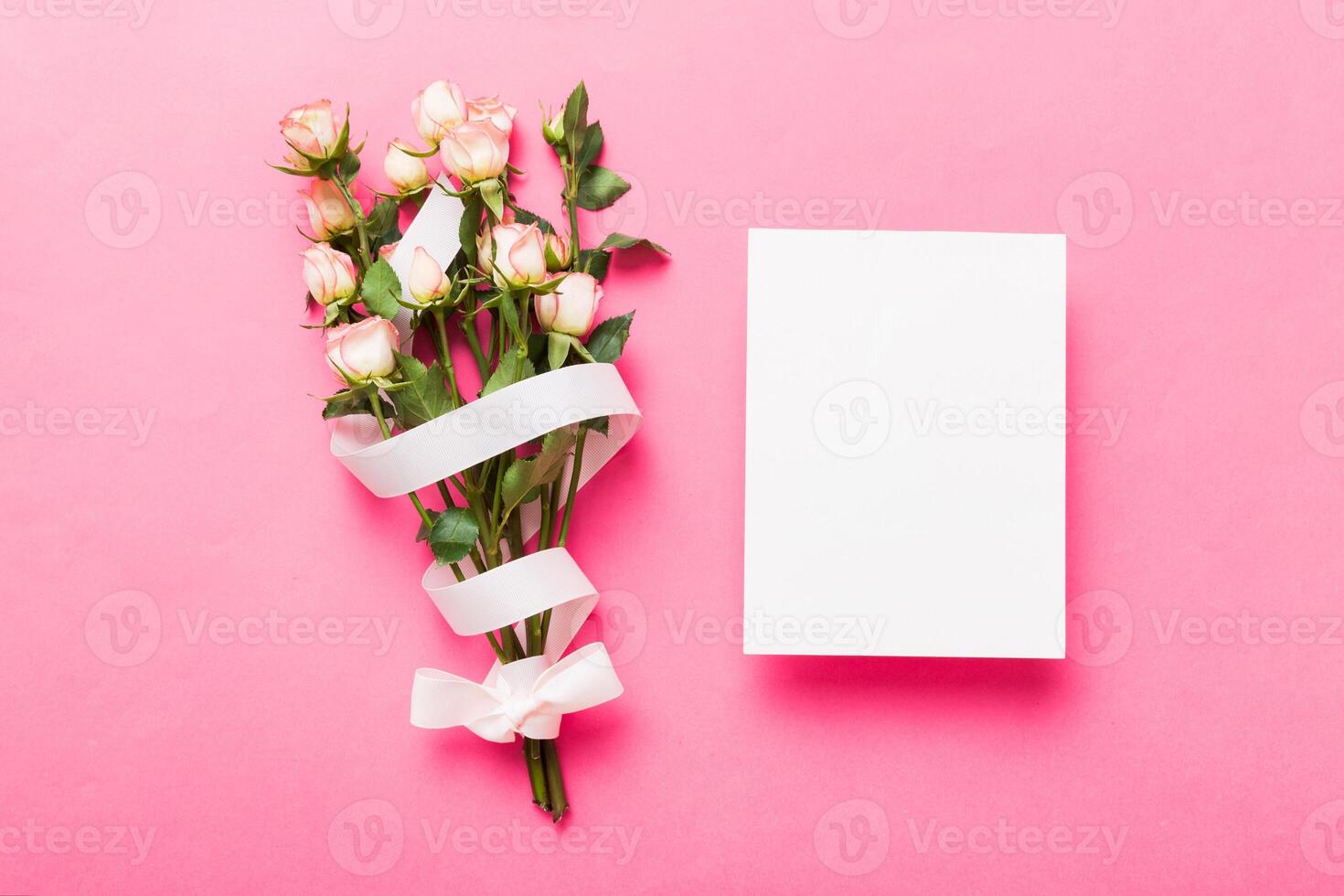 Greeting holiday card mockup with fresh roses on colored table background, mock up with copy space photo