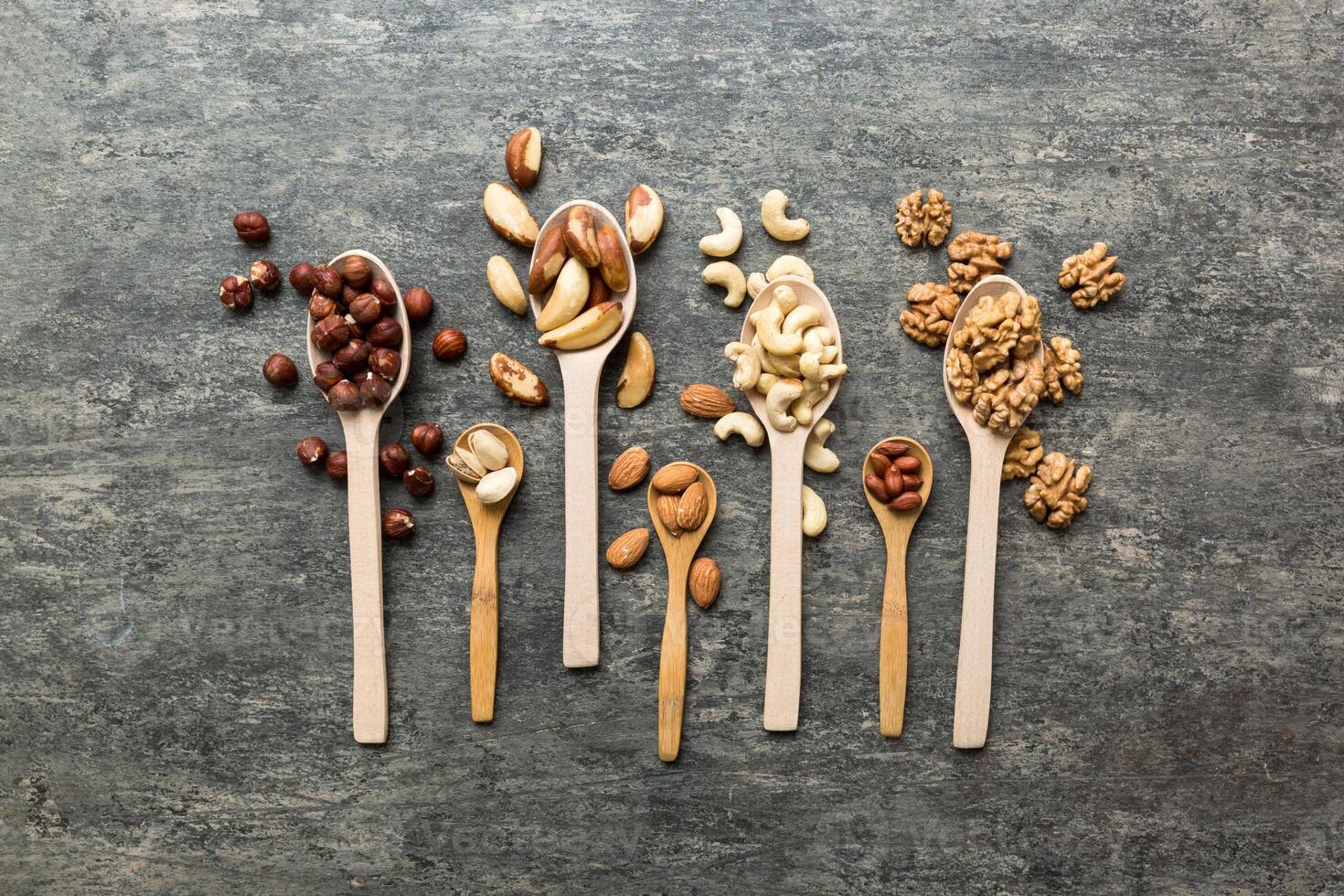 mixed nuts in white wooden spoon. Mix of various nuts on colored background. pistachios, cashews, hazelnuts, peanuts and brazil nuts photo