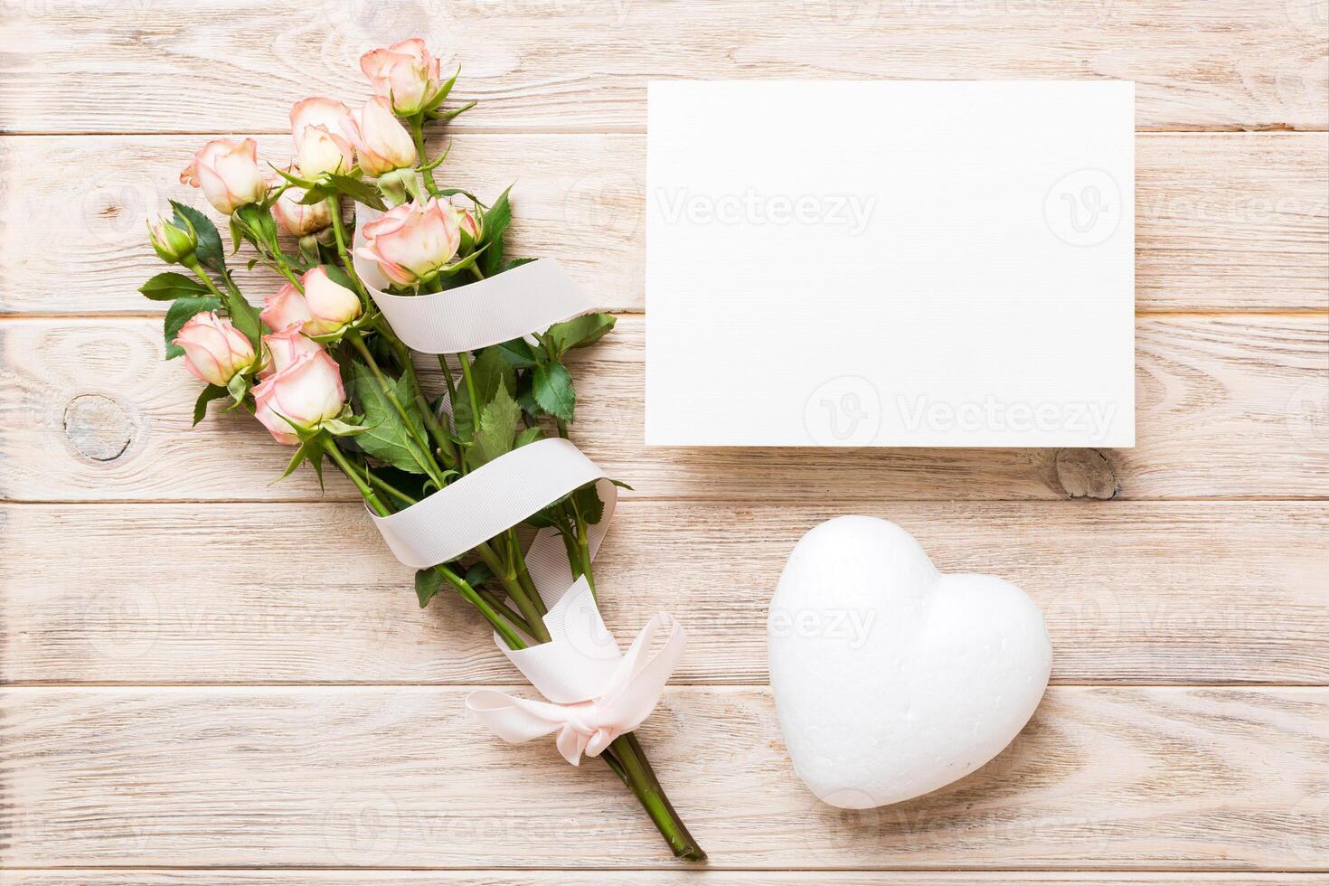 Greeting holiday card mockup with fresh roses on colored table background, mock up with copy space for design photo