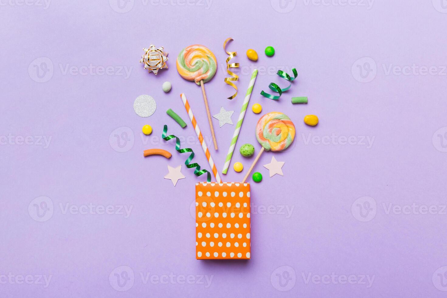 gift box in corner full assorted traditional candies falling out on colored background with copy space photo