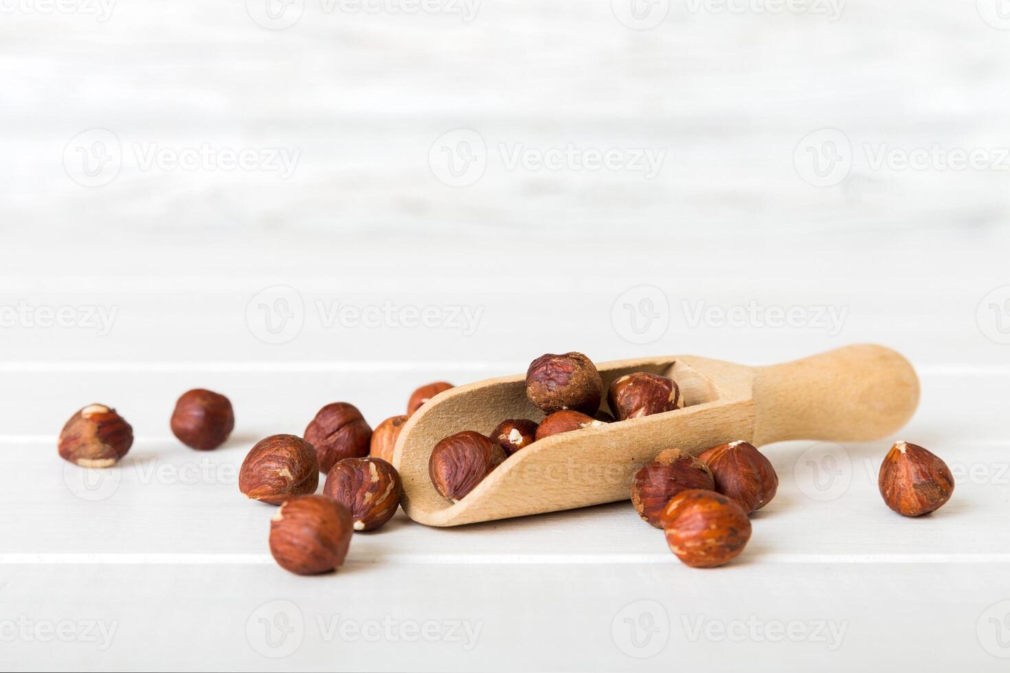 Hazelnut heap in spoon wooden table, top view photo