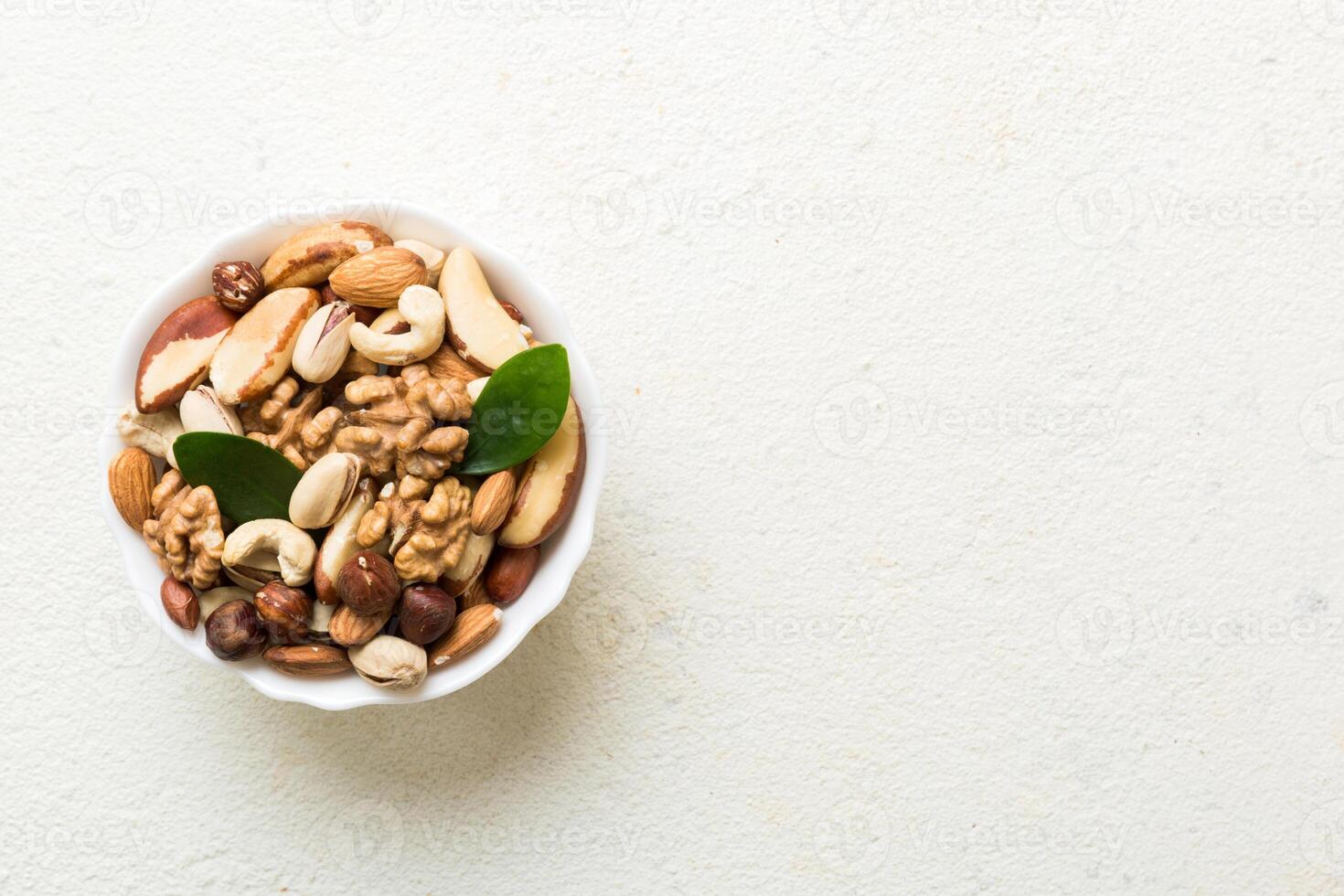 mixed nuts in bowl. Mix of various nuts on colored background. pistachios, cashews, walnuts, peanuts and brazil nuts photo