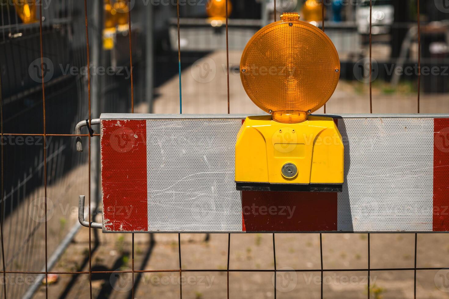 Bright yellow warning light shines on construction barrier at an active worksite in the warm afternoon sun photo