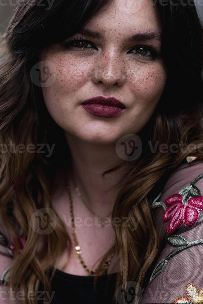Woman with freckles and floral top poses for portrait in natural light photo