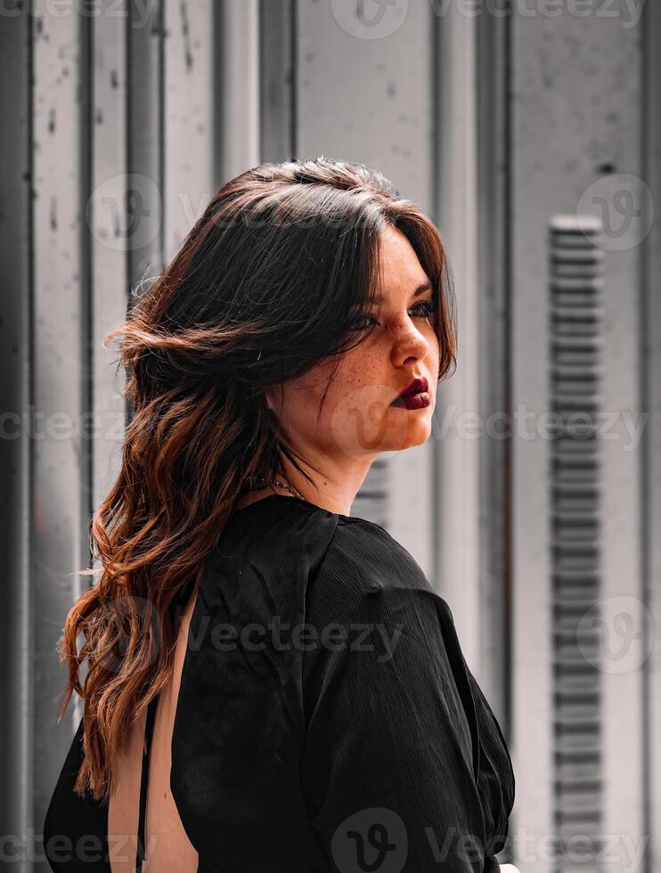 Striking pose of a woman with flowing hair against an urban backdrop showcasing elegance and self-expression in natural light photo