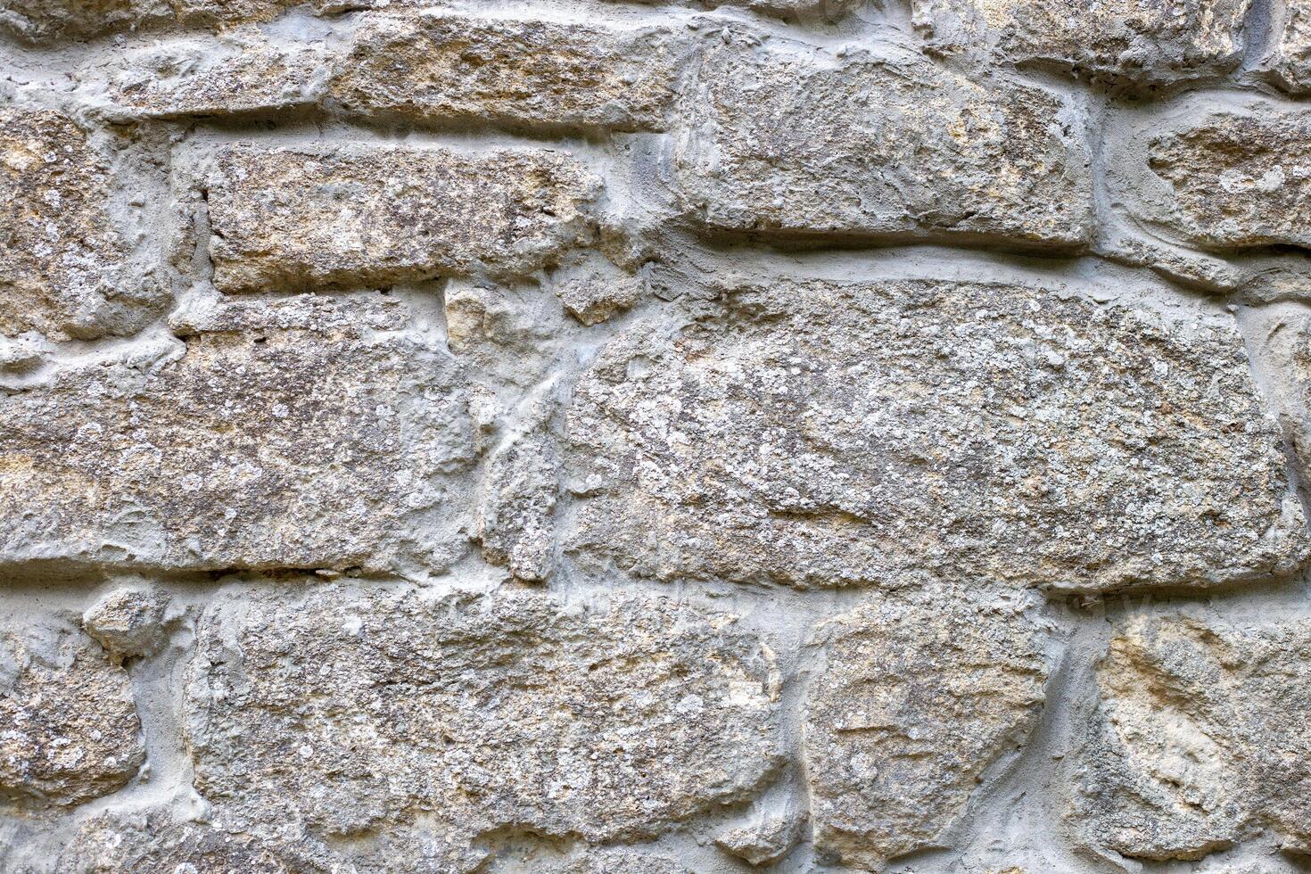 Closeup of a section of masonry with gray, uneven stones held together with cement mortar to form a textured background photo