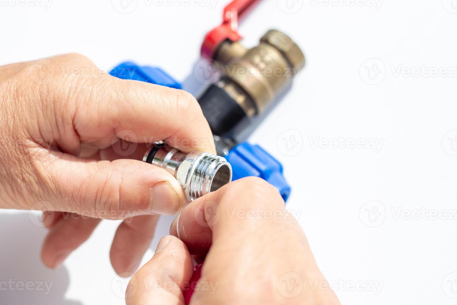close-up of hands assembling metal threaded part with plastic fittings and valve, winding fumka, sealing tape photo