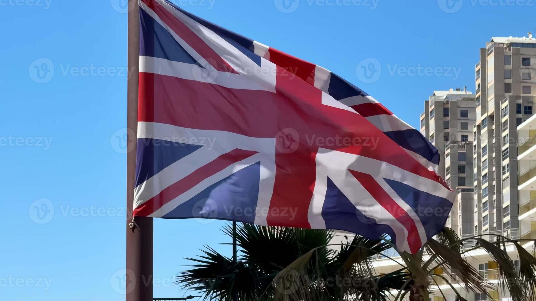 A vibrant Union Jack flag is waving gracefully in the gentle breeze beneath a picturesque bright blue sky photo