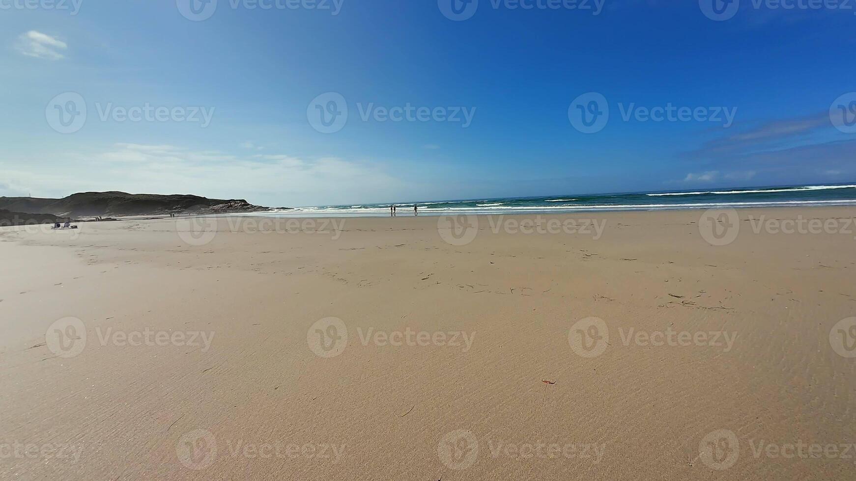 A stunning beach scene beautifully showcasing soft golden sand, gentle waves, and a bright, clear blue sky photo