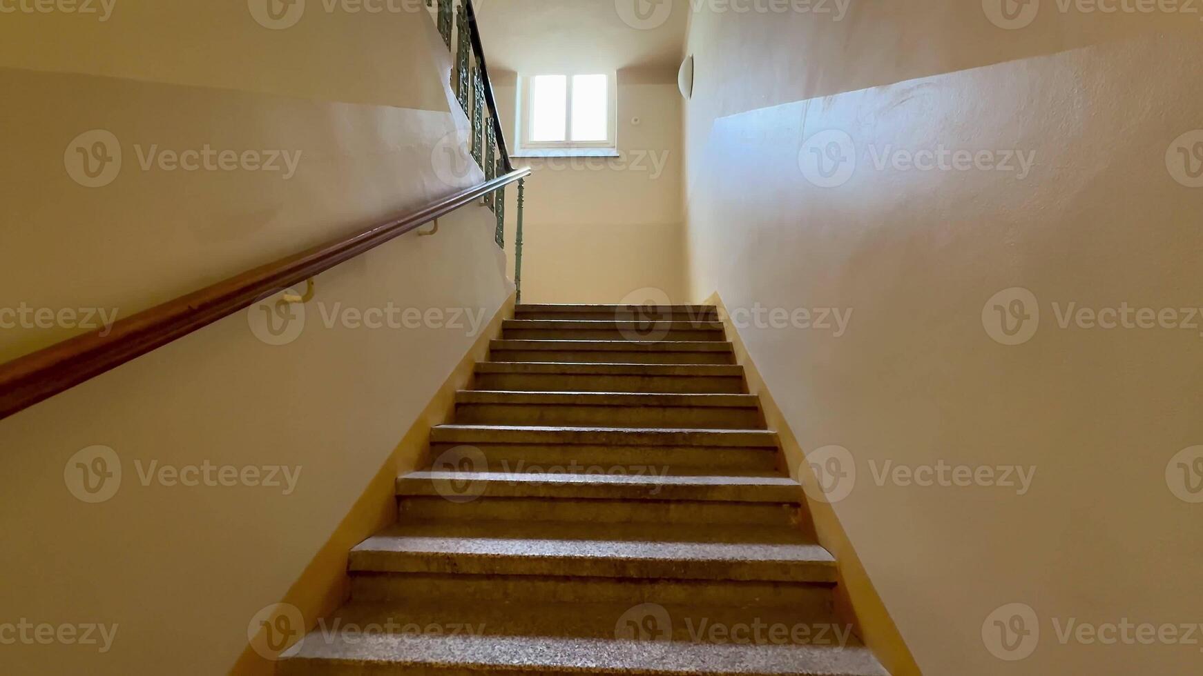 A serene and beautiful view of a welllit, elegant stairway that gracefully leads to a bright window positioned above photo