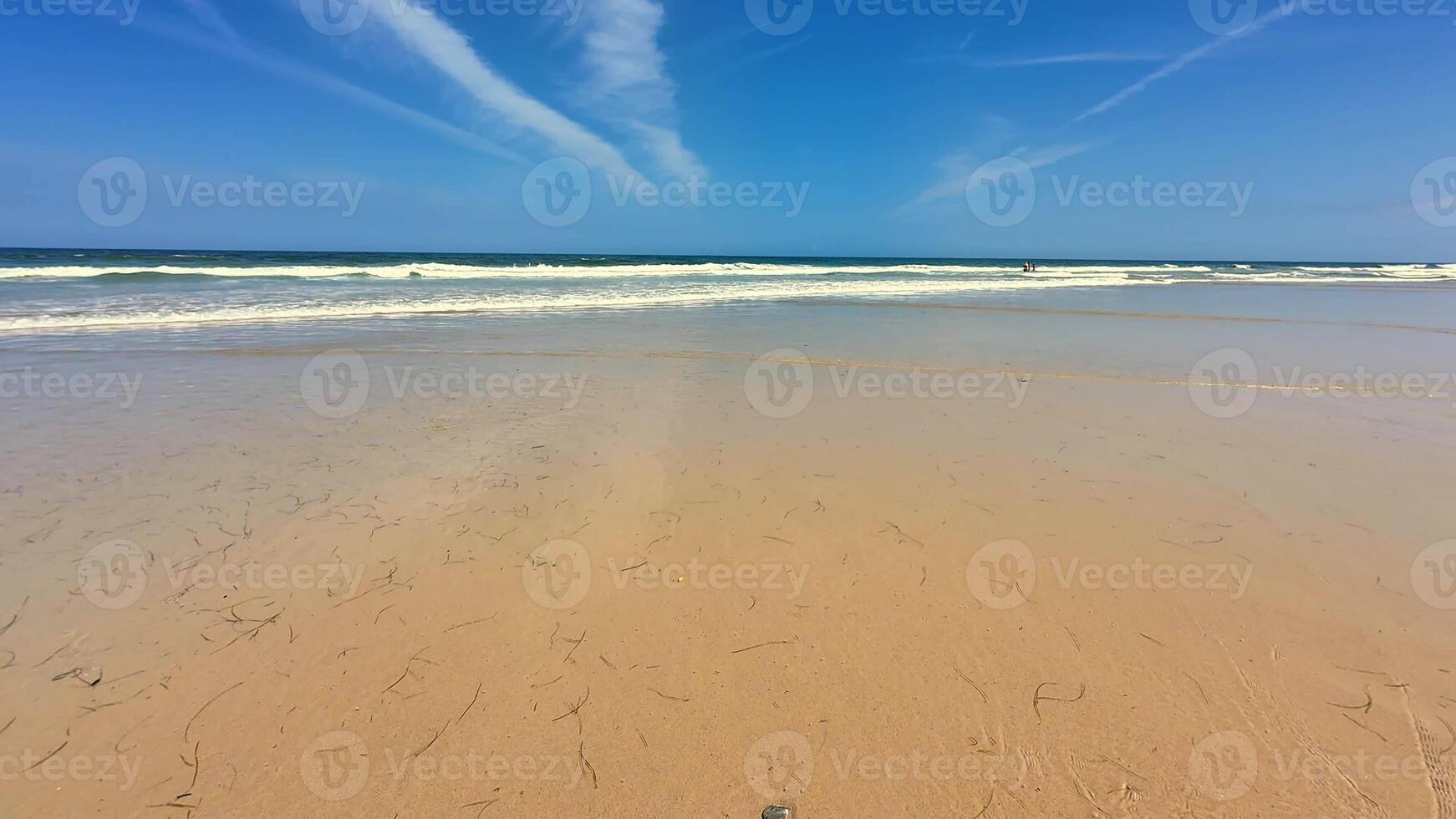 A tranquil beach scene vividly showcasing gentle waves lapping against the shore and a beautiful blue sky overhead photo