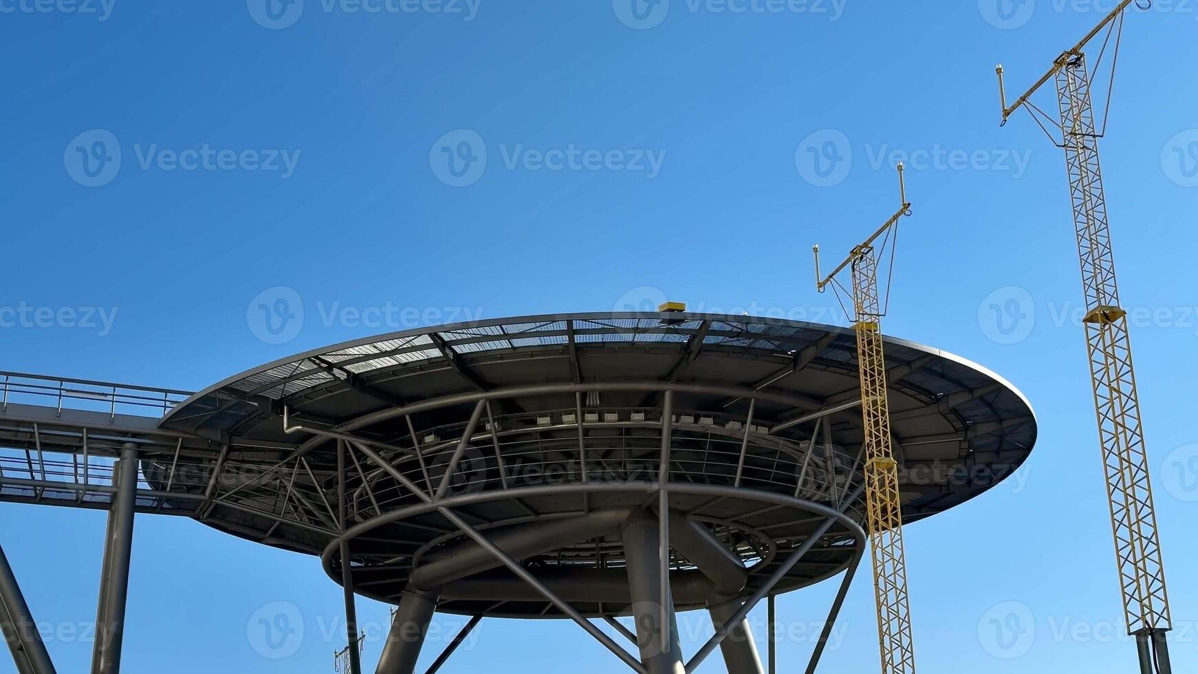 A modern architectural design featuring a circular shape set against a stunning backdrop of a clear blue sky photo
